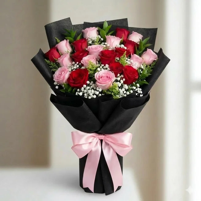 Red and pink roses bouquet wrapped in elegant black paper with baby’s breath fillers